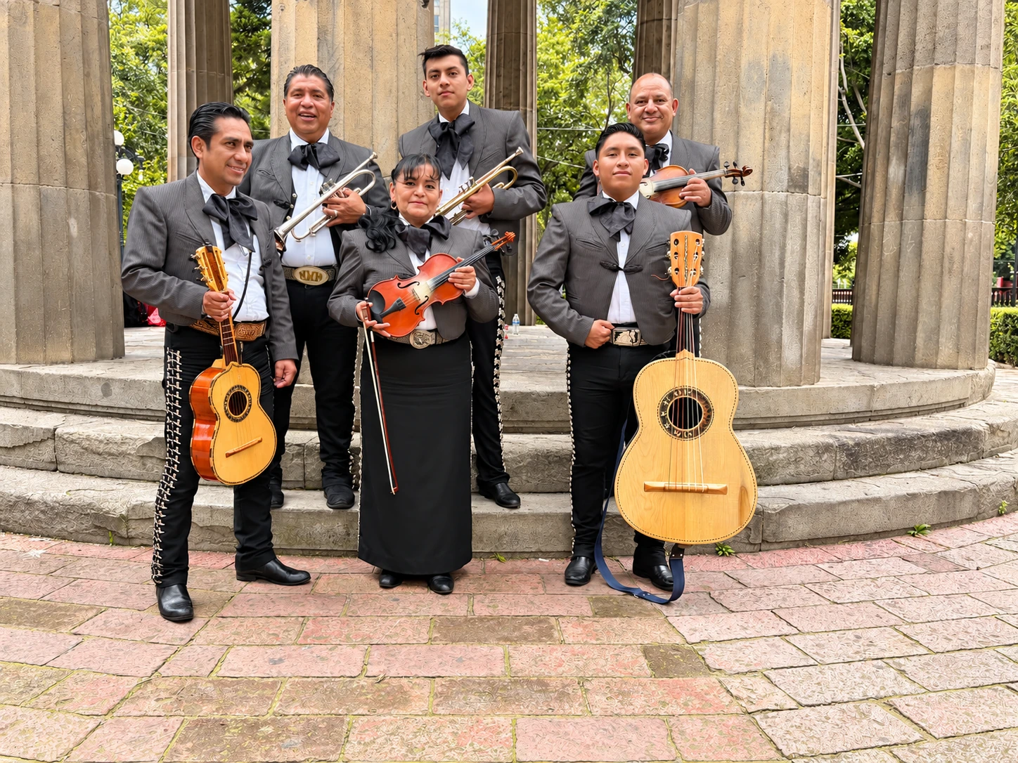 Integrantes de Mariachi Estelar con sus instrumentos frente a columnas de piedra
